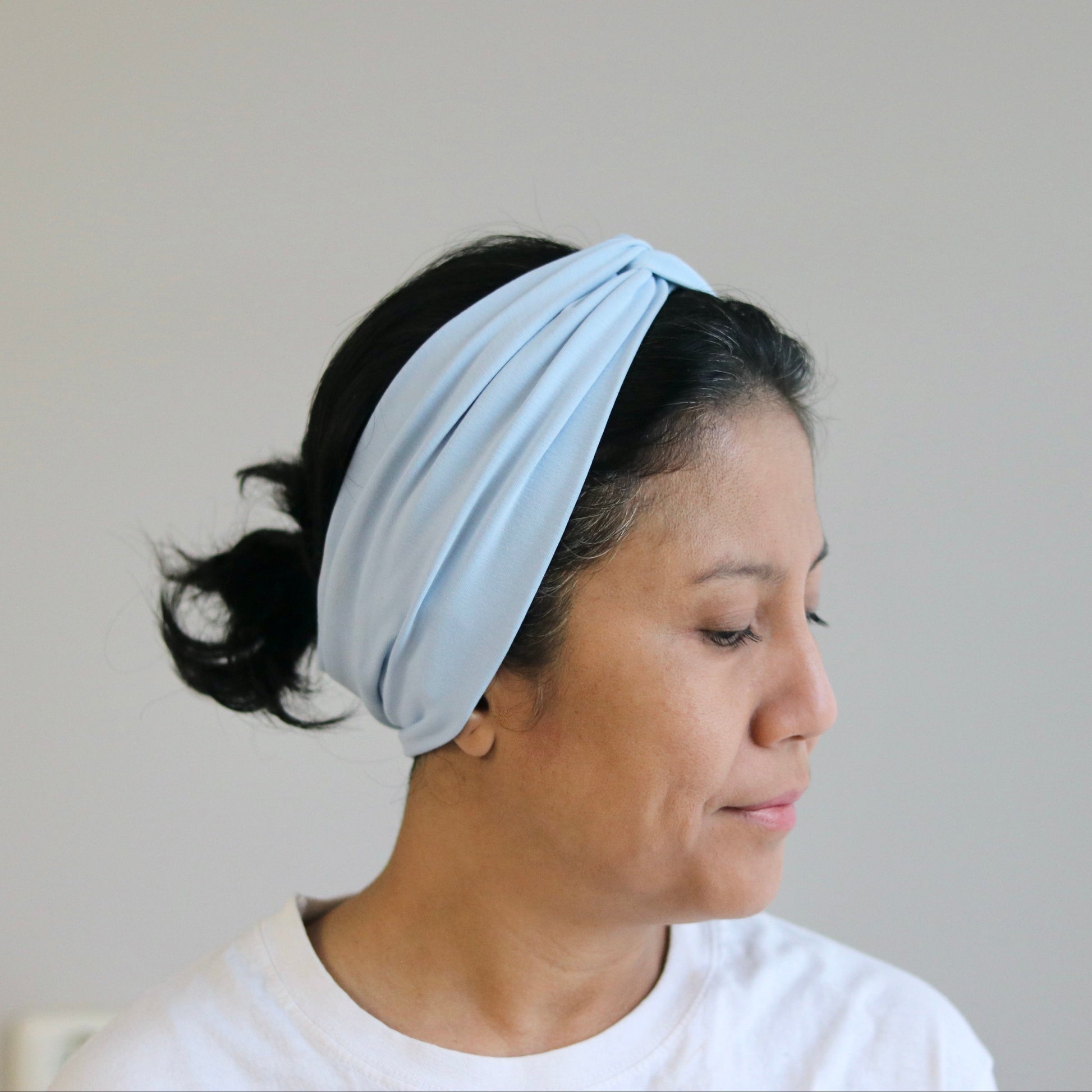 Woman wearing a light blue headband against a plain background