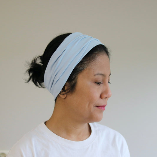 Woman wearing a light blue headband against a plain background