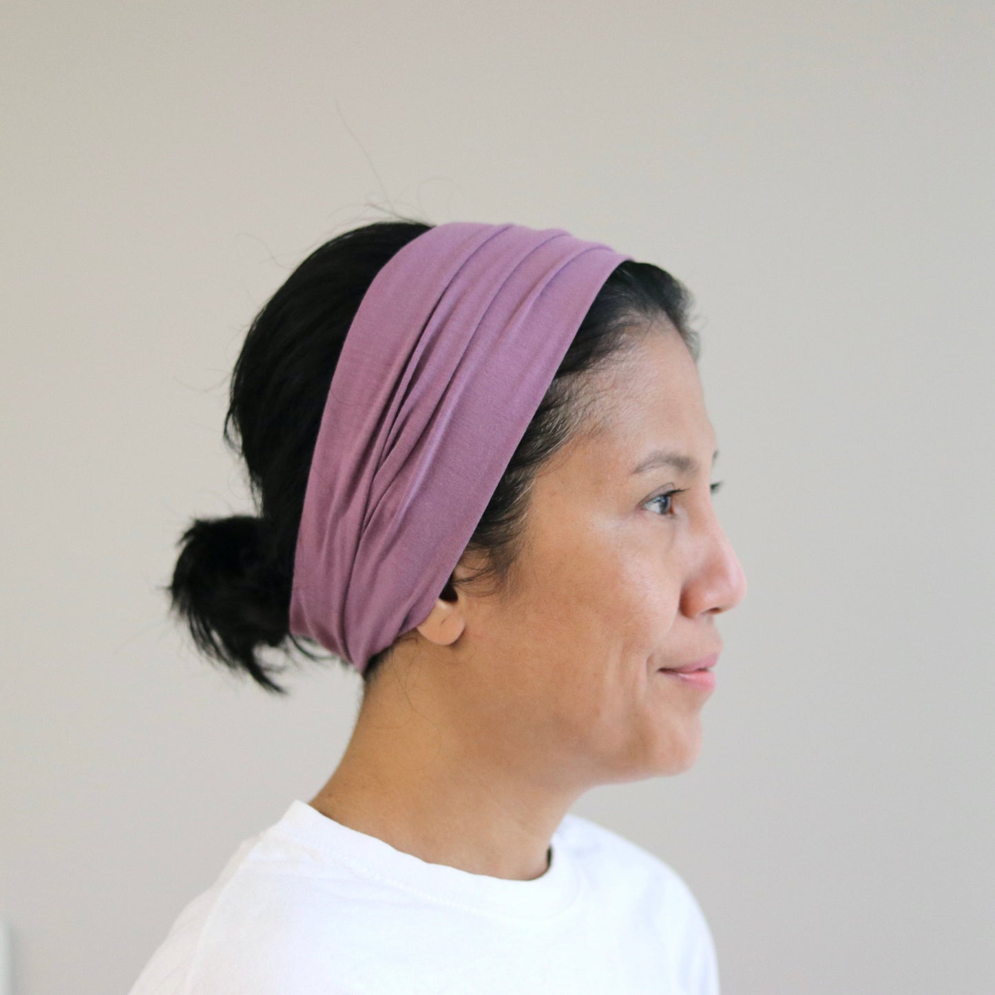 Woman wearing a purple headband against a plain background
