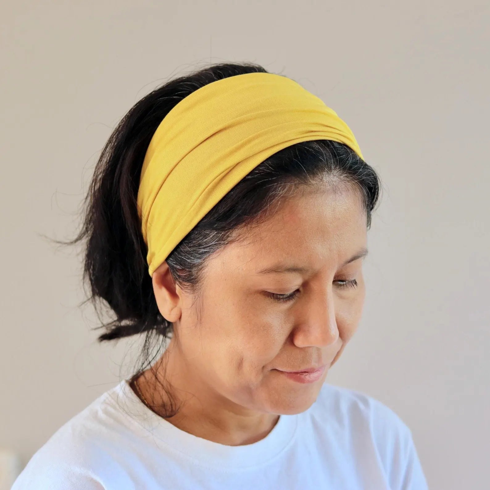 Woman wearing a yellow bamboo headband against a plain background