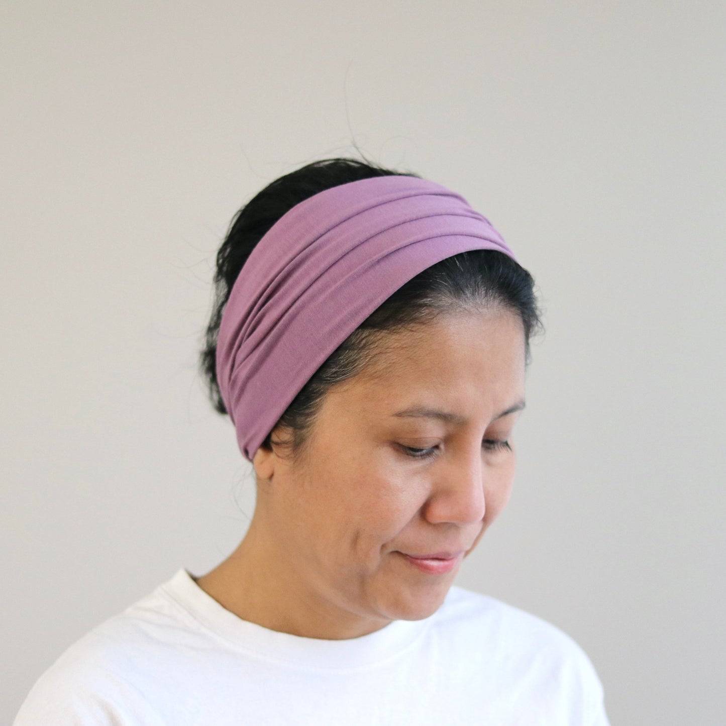 Woman wearing a purple headband against a plain background