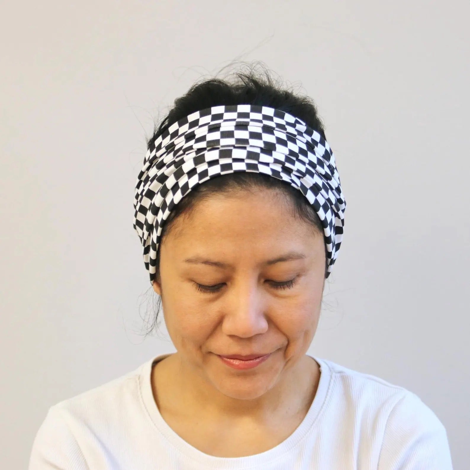 Person wearing a black and white checkered headband against a plain background