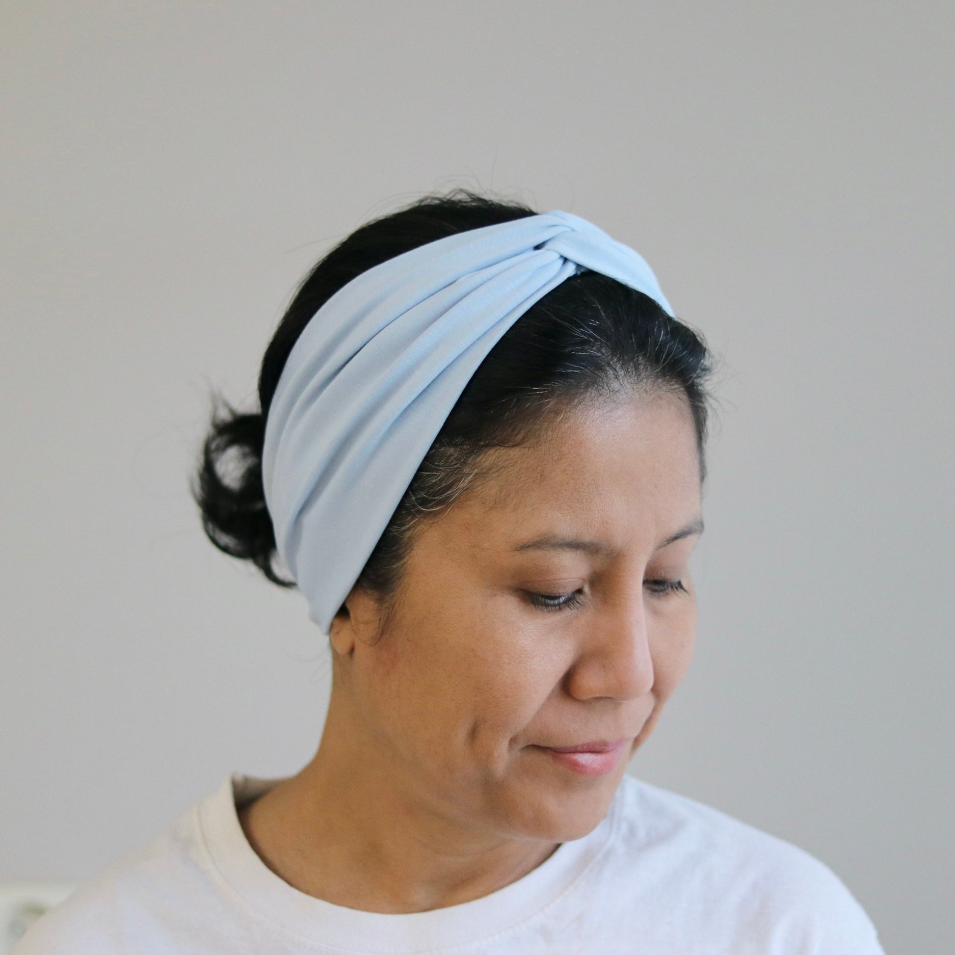 Woman wearing a light blue headband against a plain background