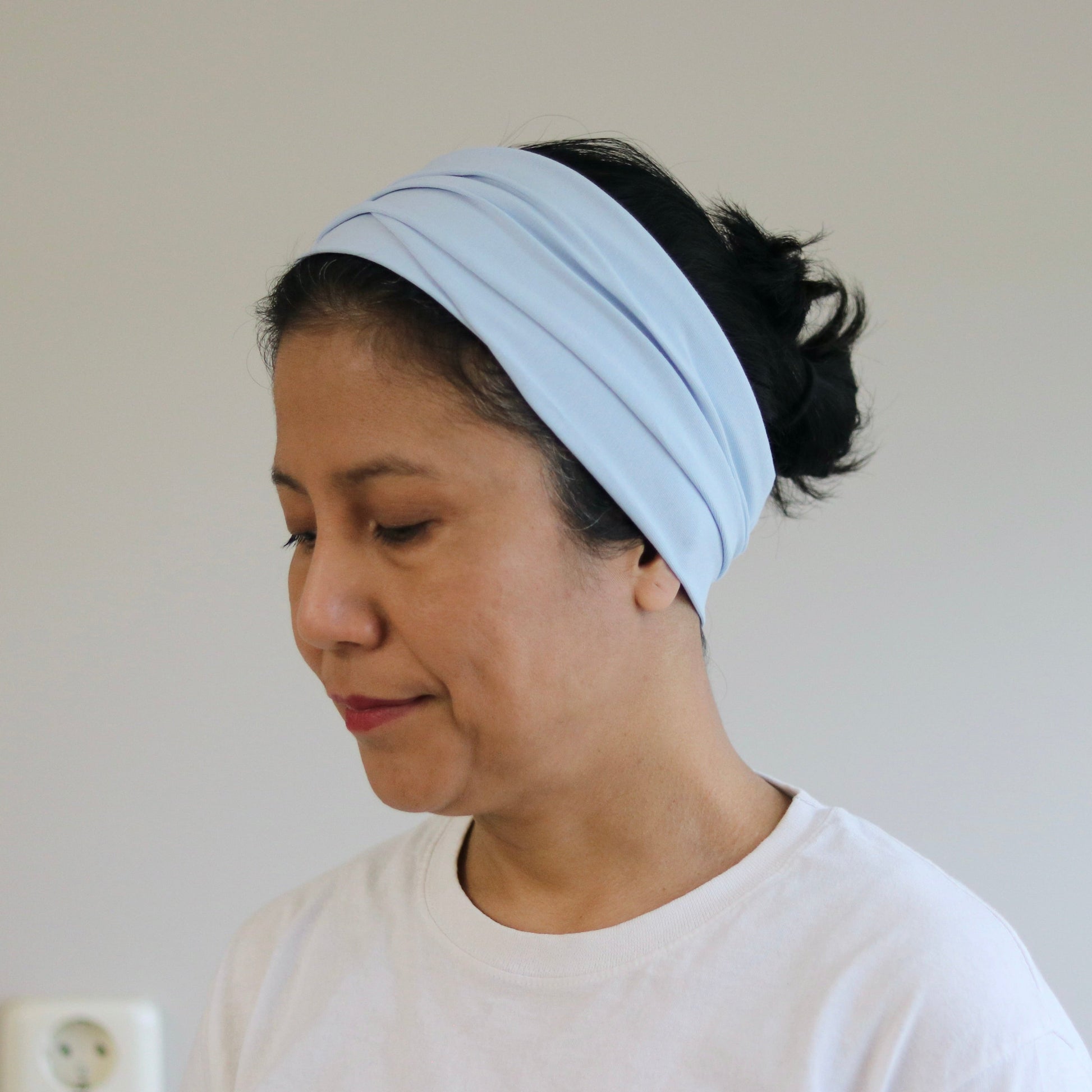 Woman wearing a light blue headband against a plain background