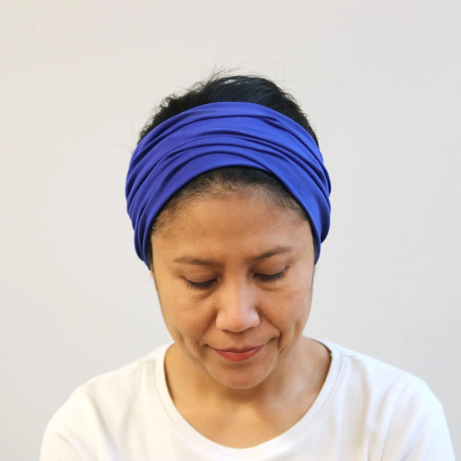 Person wearing a blue headband against a plain background