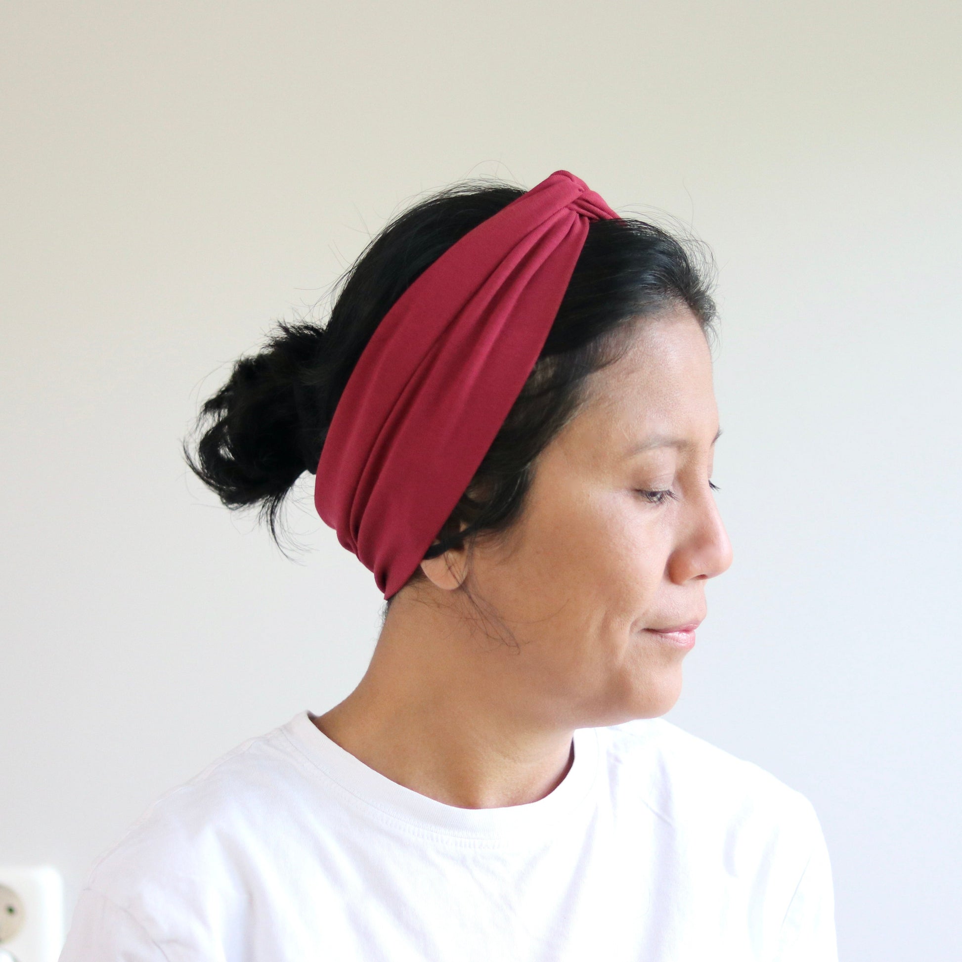 Woman wearing a bordeaux headband against a plain background