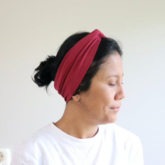 Woman wearing a bordeaux headband against a plain background