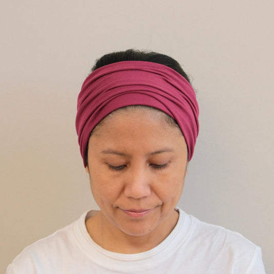 Person wearing a Bordeaux headband against a plain background