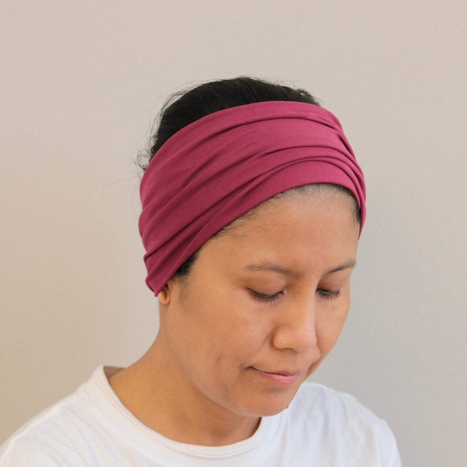 Woman wearing a Bordeaux headband against a plain background