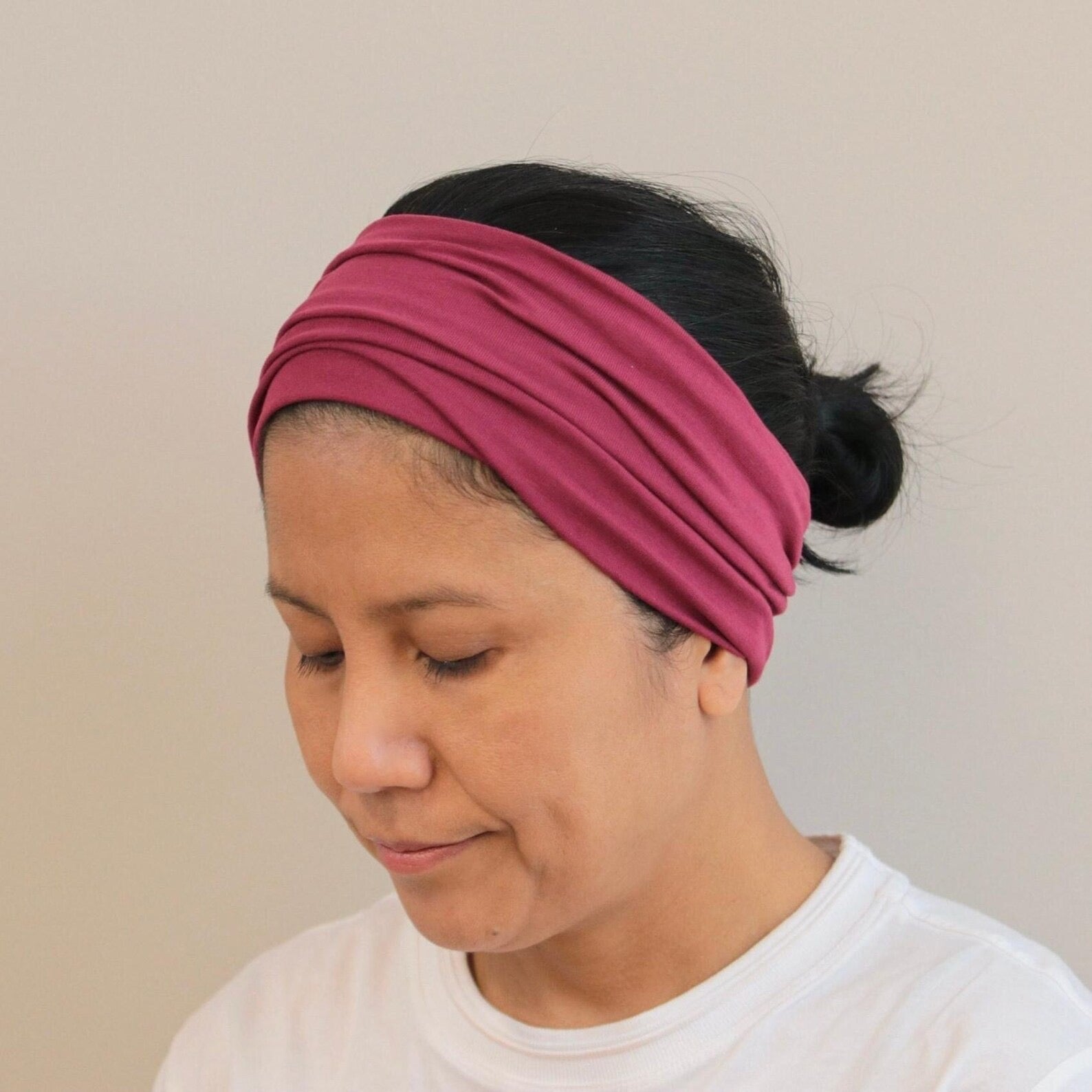 Woman wearing a bordeaux headband against a beige background