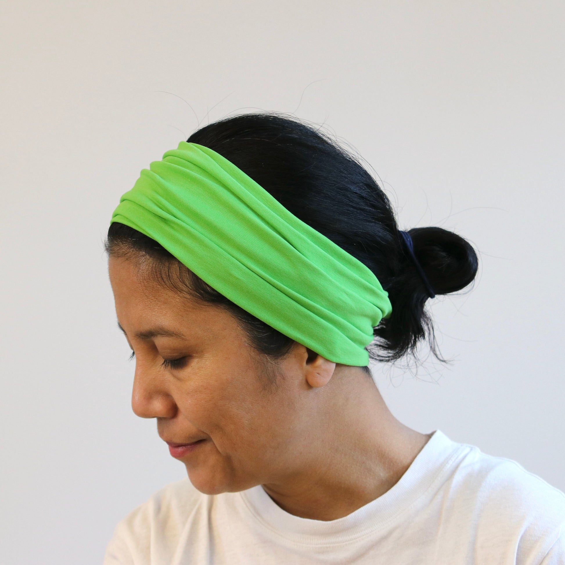 Woman wearing a bright green headband against a plain background