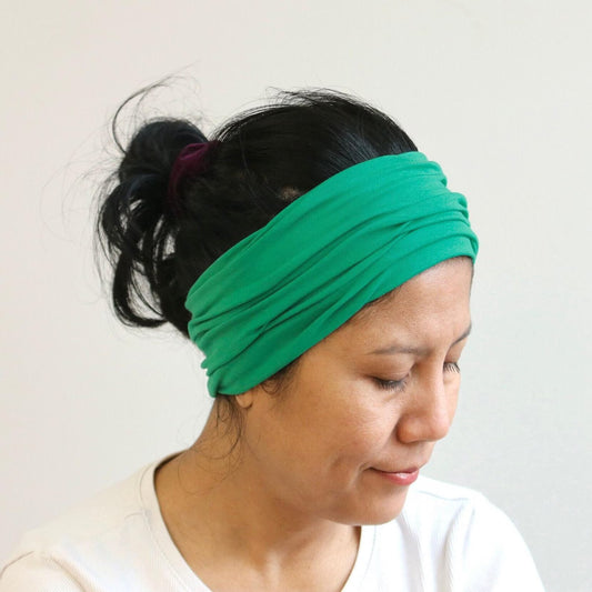 Woman wearing a green headband against a plain background