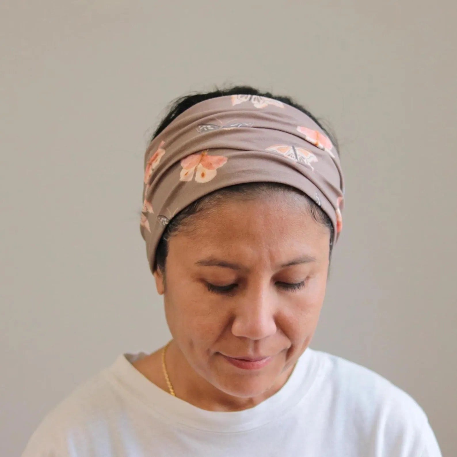 Woman wearing a patterned headband against a plain background