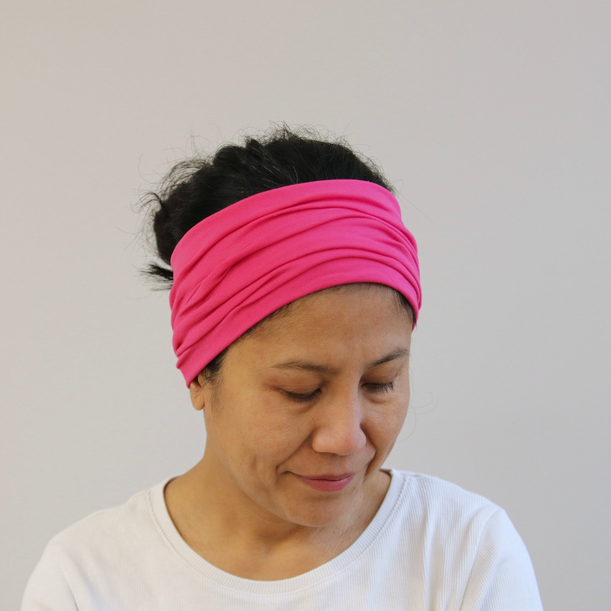 Person wearing a pink headband against a plain background