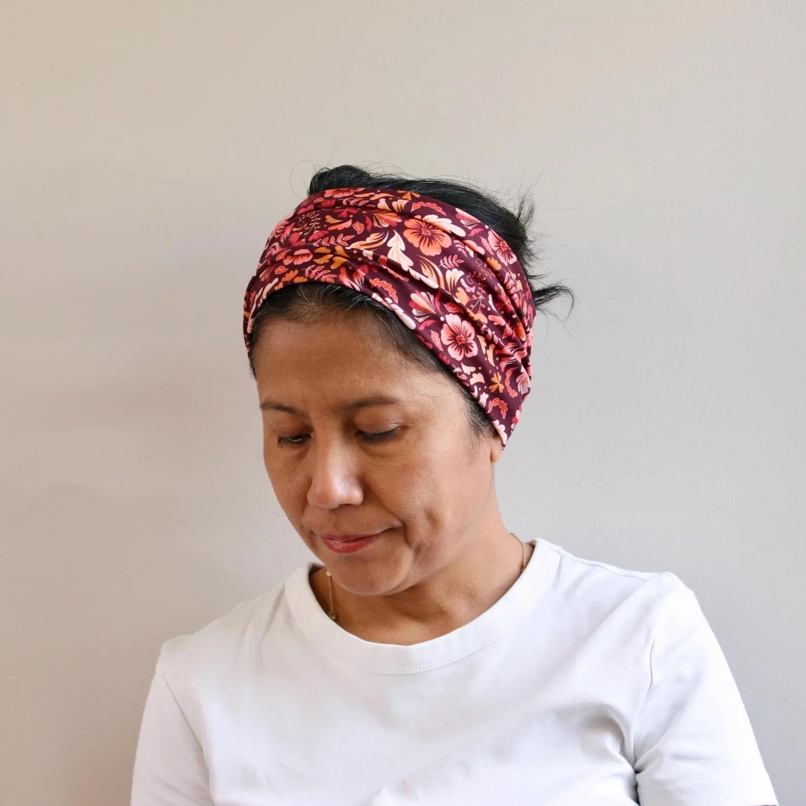 Woman wearing a pink floral headband against a plain background