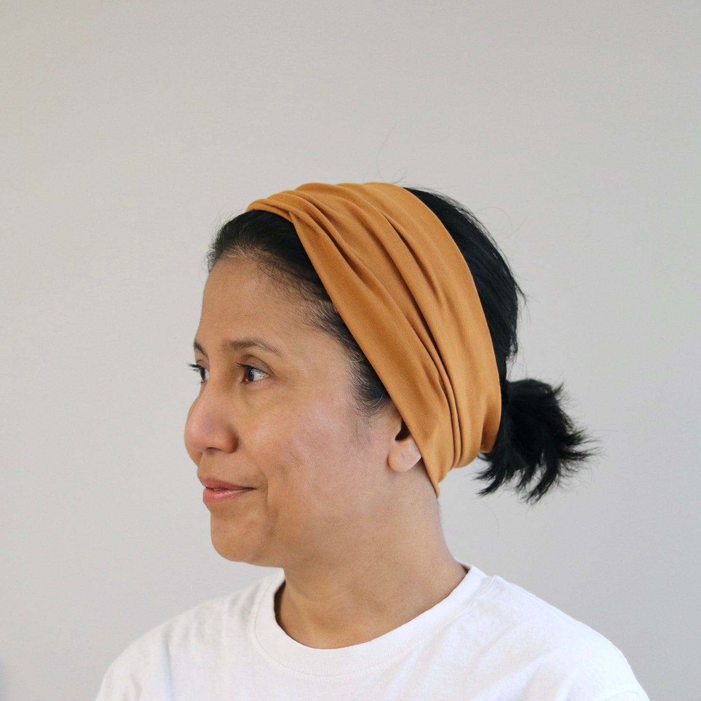 Woman wearing a cooper- blush headband against a plain background