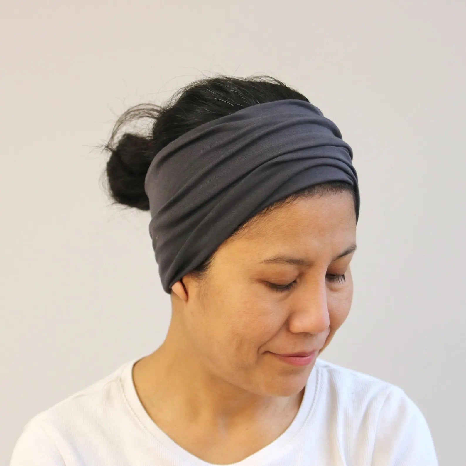 Woman wearing a gray headband against a plain background