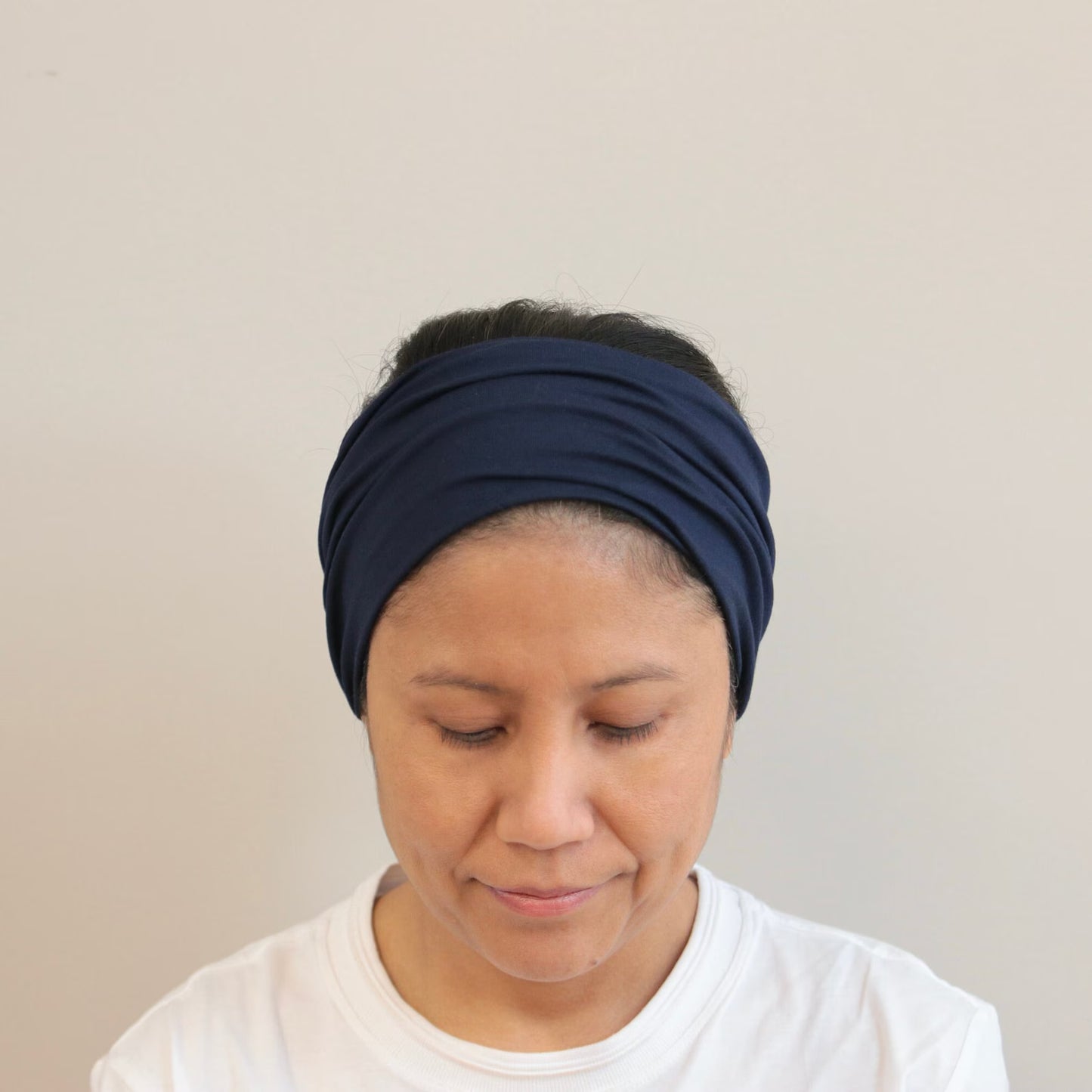 Woman wearing a navy blue headband against a plain background