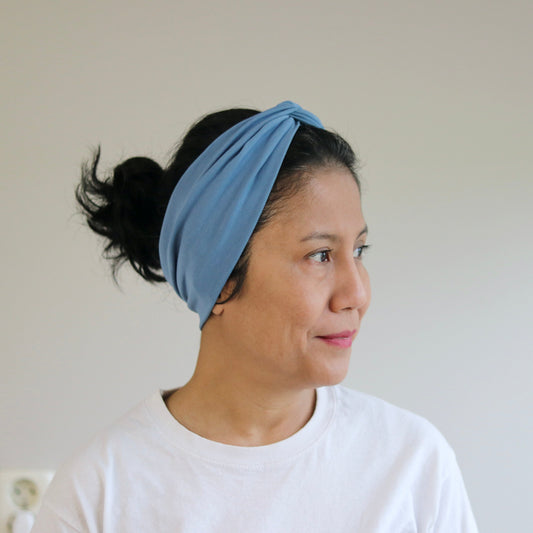 Woman wearing a blue headband against a plain background
