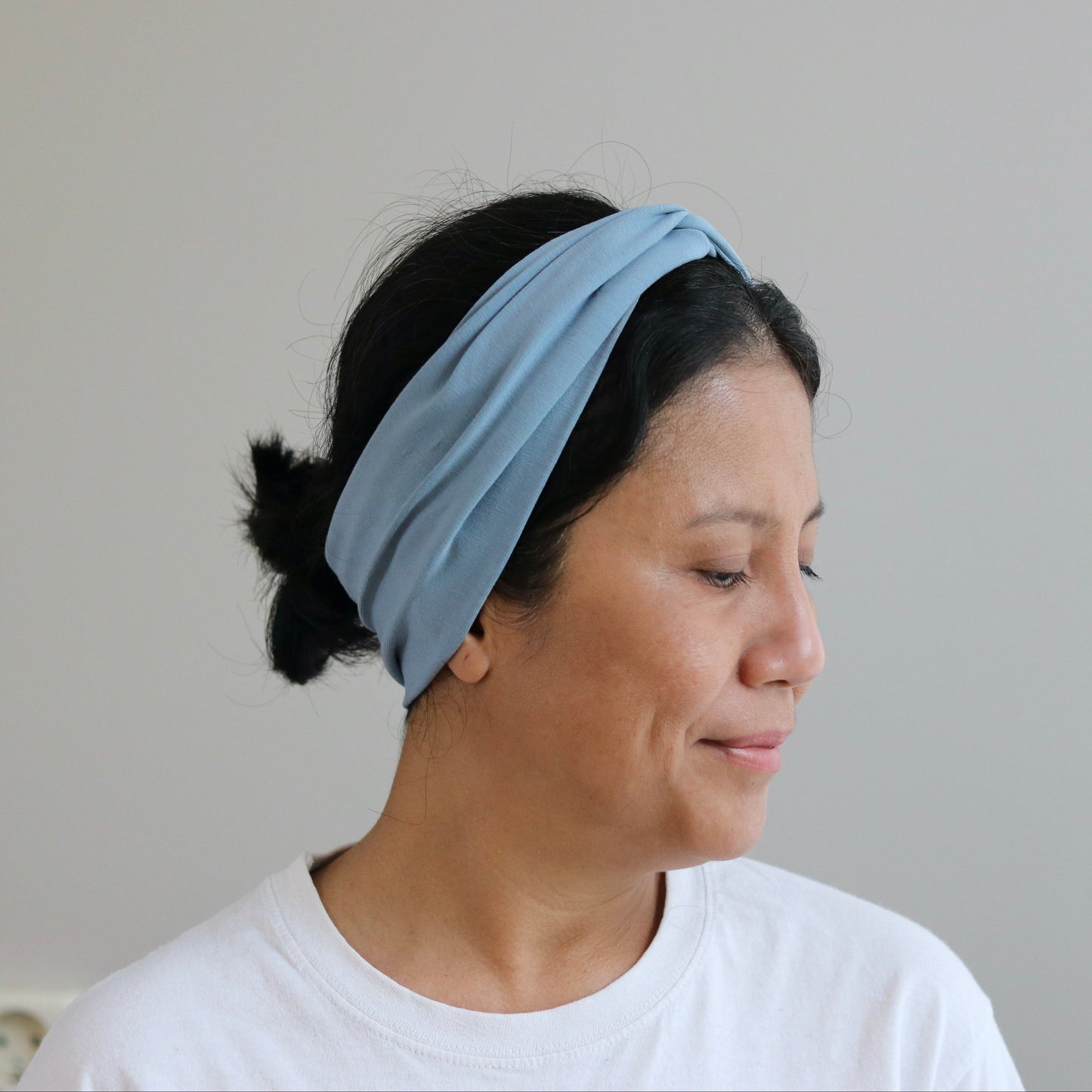 Woman wearing a light blue headband against a plain background