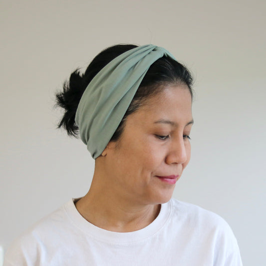 Woman wearing a green headband against a plain background