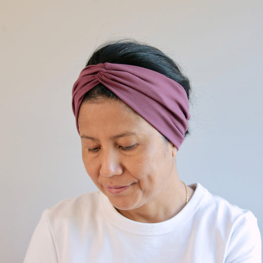 Woman wearing a purple headband against a plain background