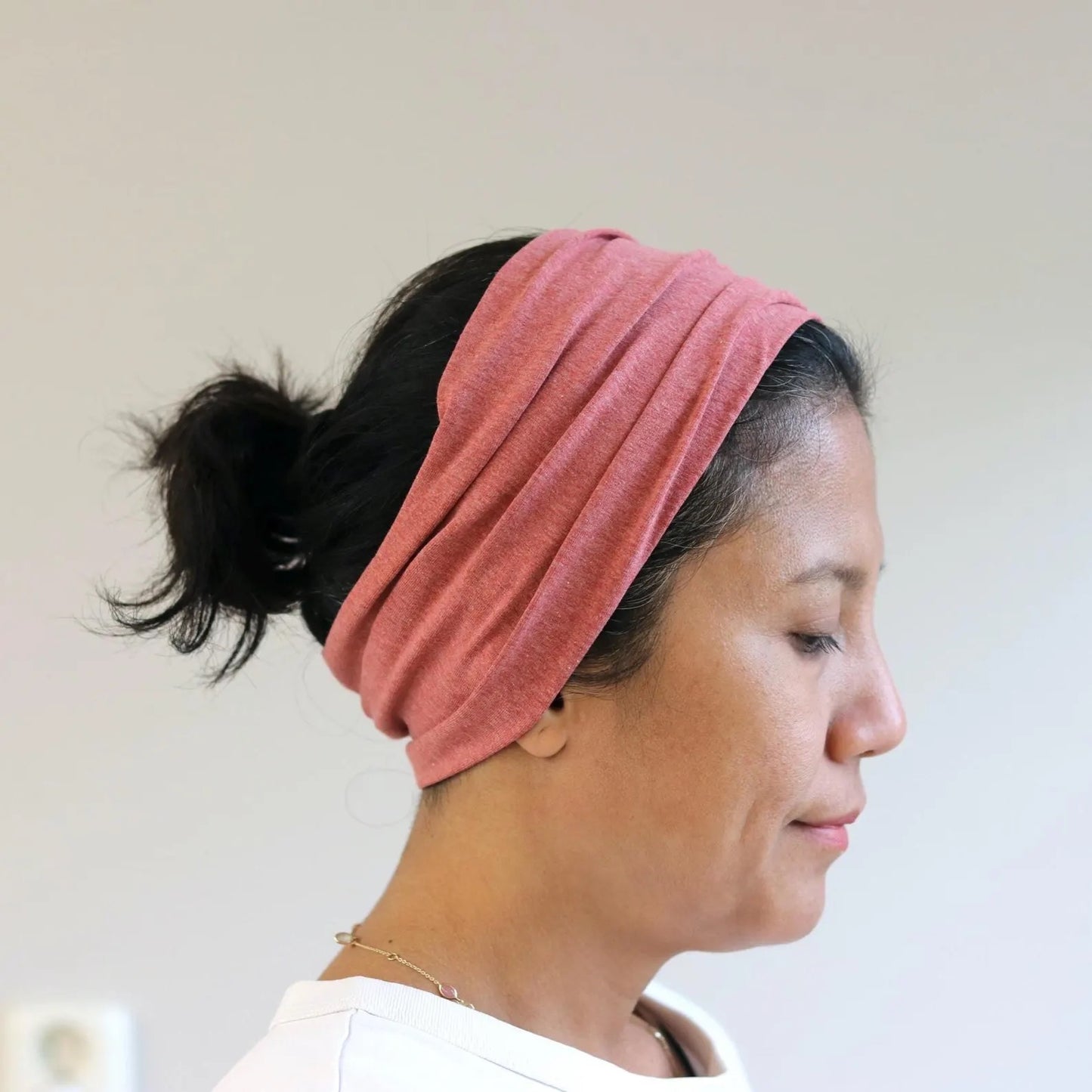 Woman wearing a red- melange headband against a plain background