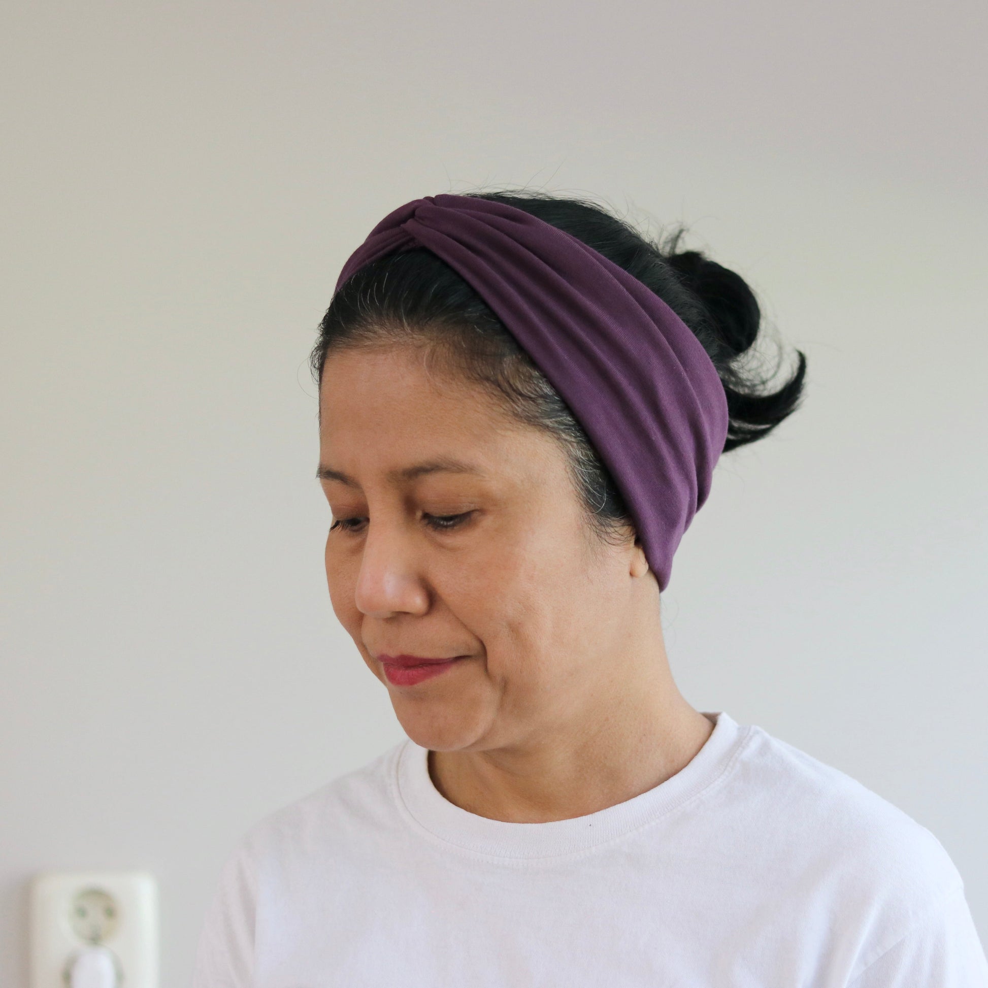 Woman wearing a purple headband against a plain background