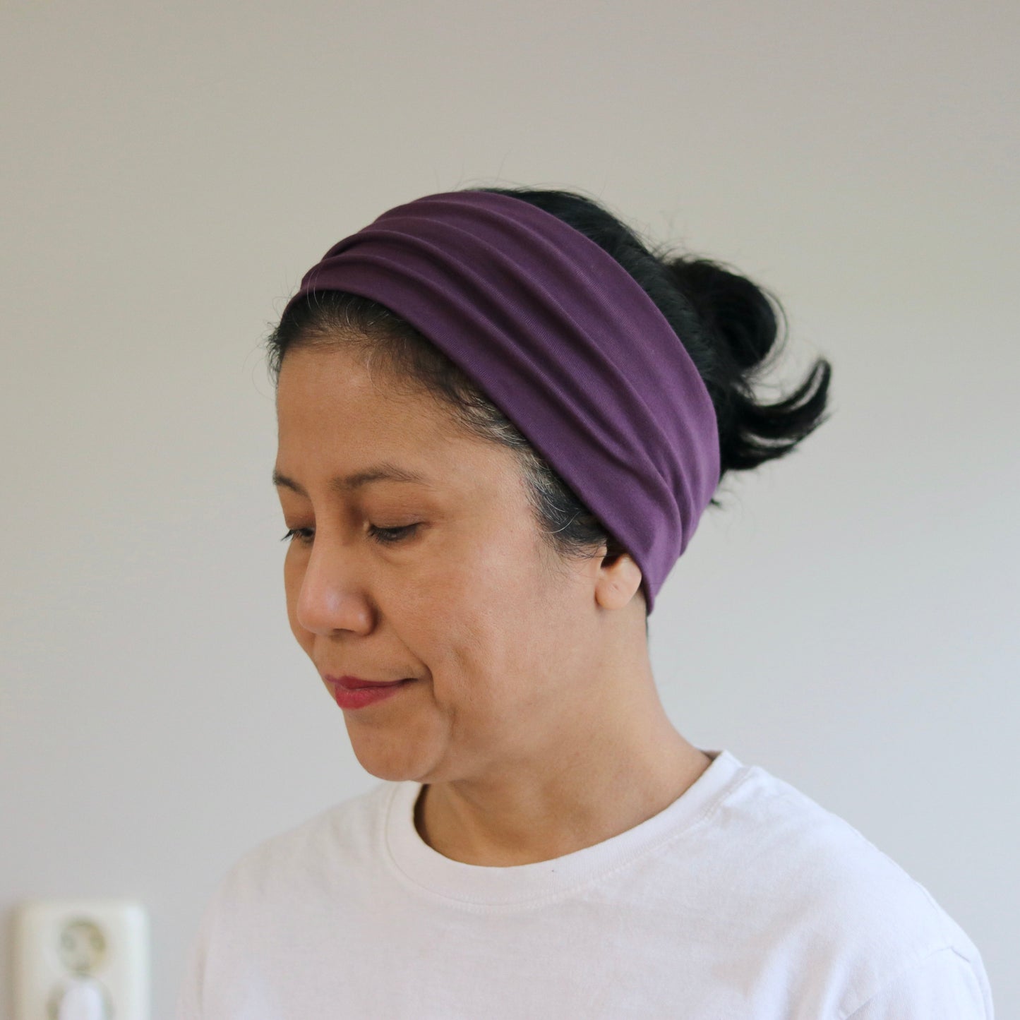 Woman wearing a purple headband against a plain background