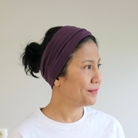 Woman wearing a purple headband against a plain background
