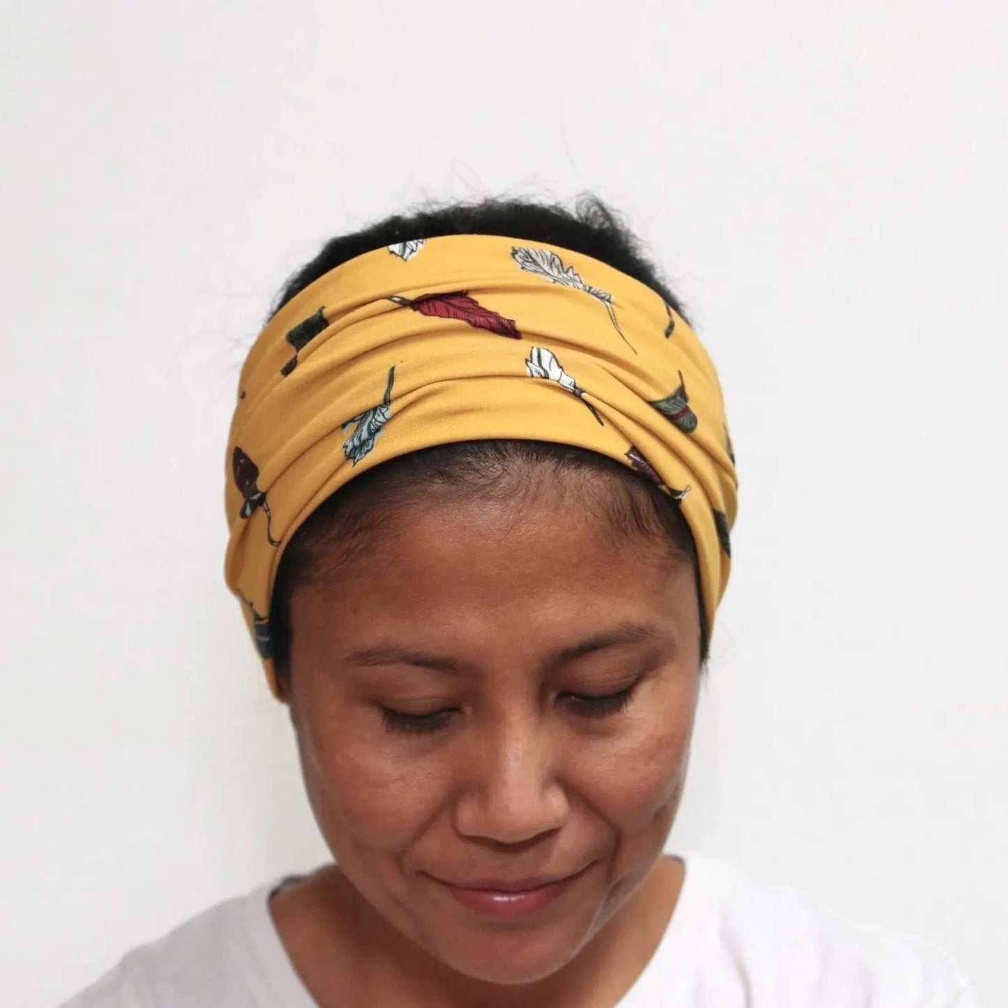 Person wearing a yellow headband with feathers prints on a white background
