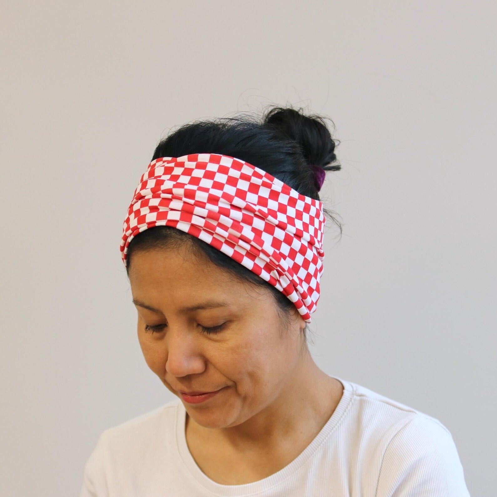 Person wearing a red and white checkered headband against a plain background