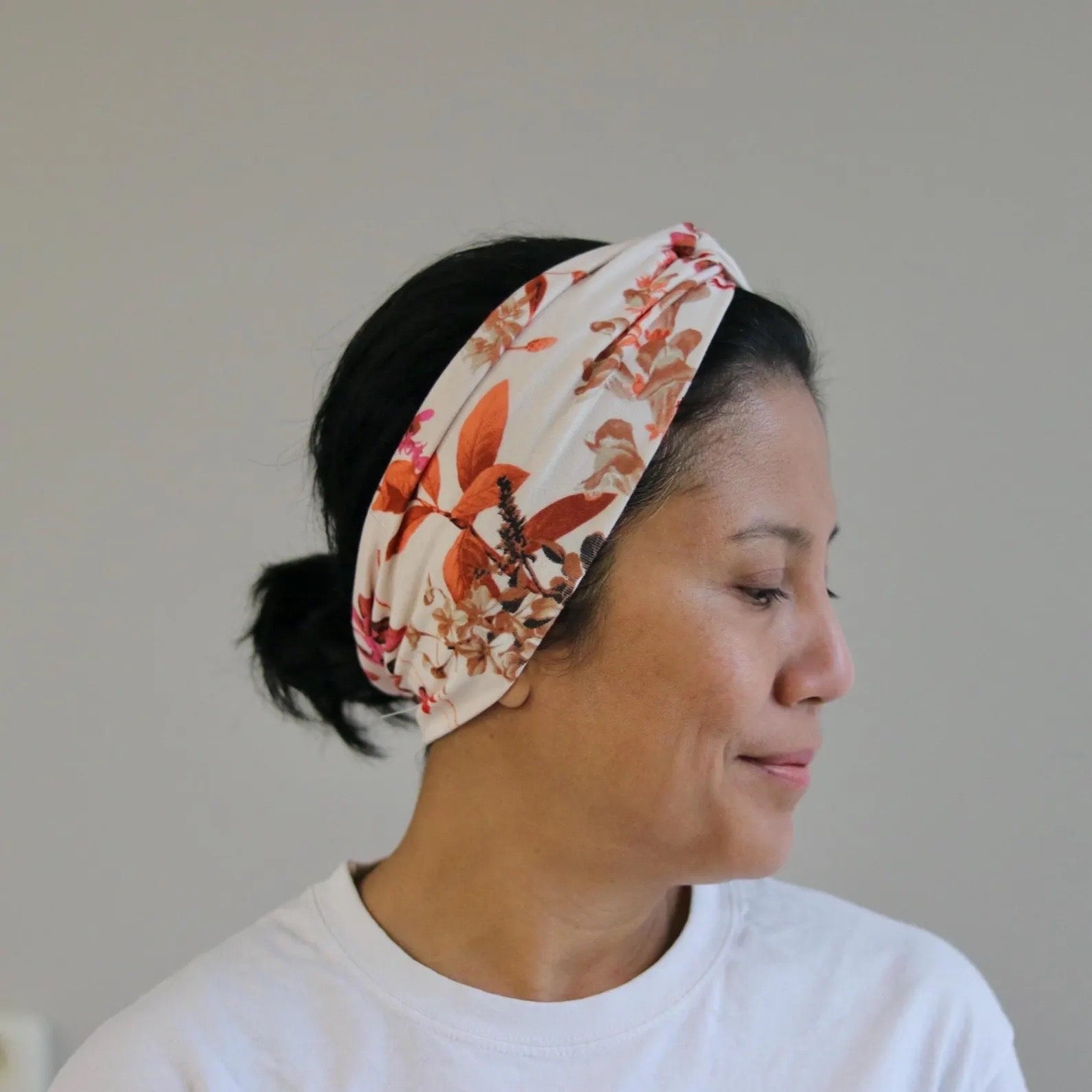 Woman wearing a floral headband against a plain background