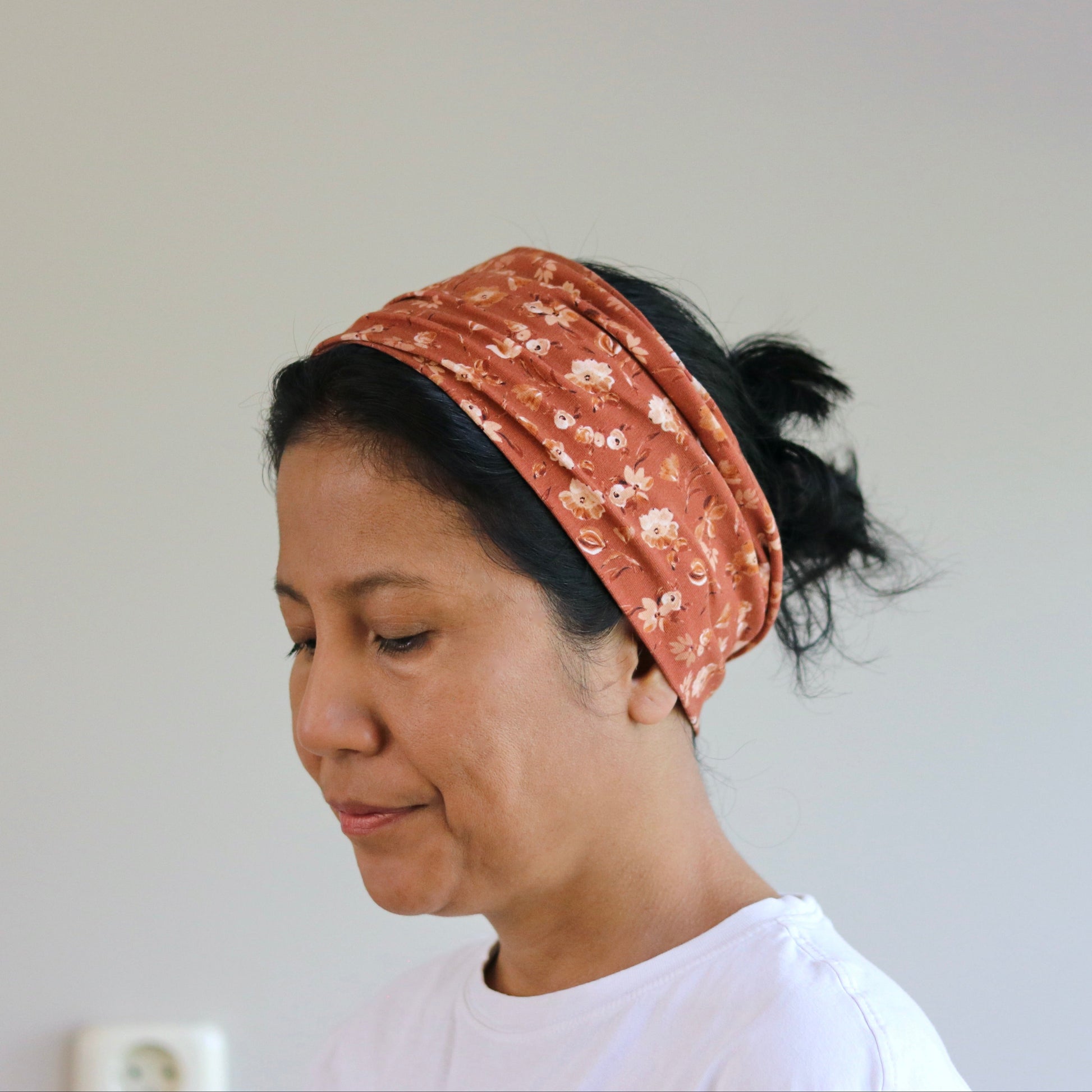 Woman wearing a patterned headband against a plain background