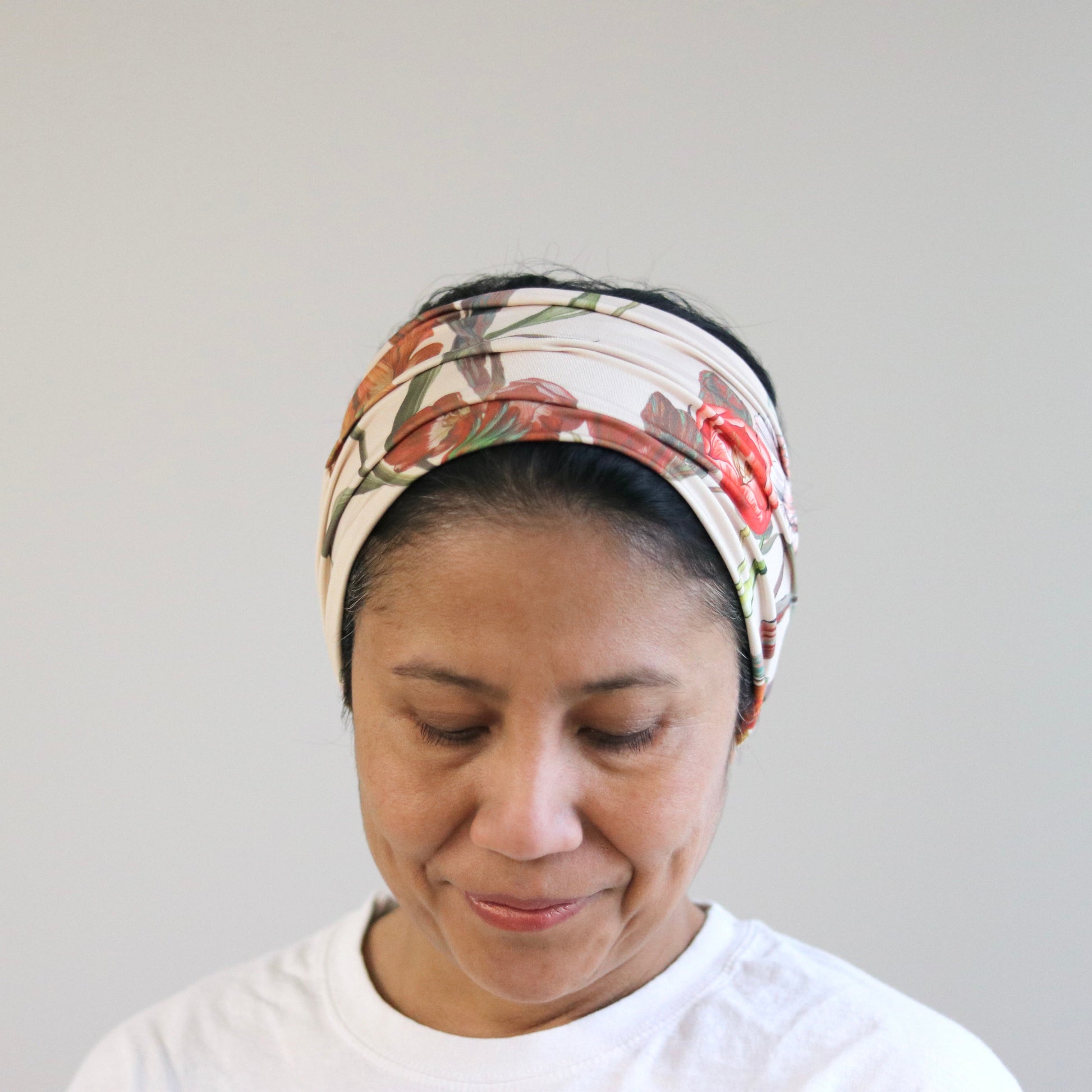 Woman wearing a floral headscarf against a plain background