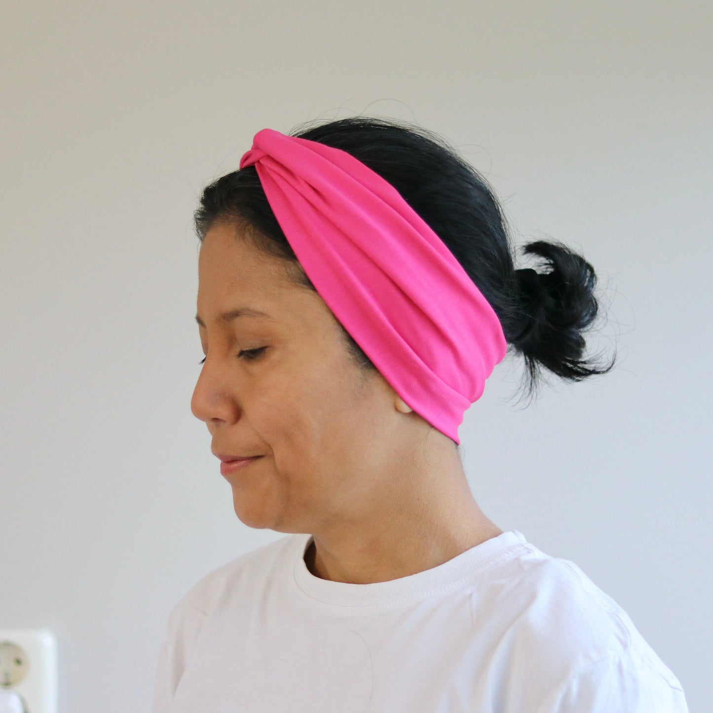 Woman wearing a pink headband against a plain background
