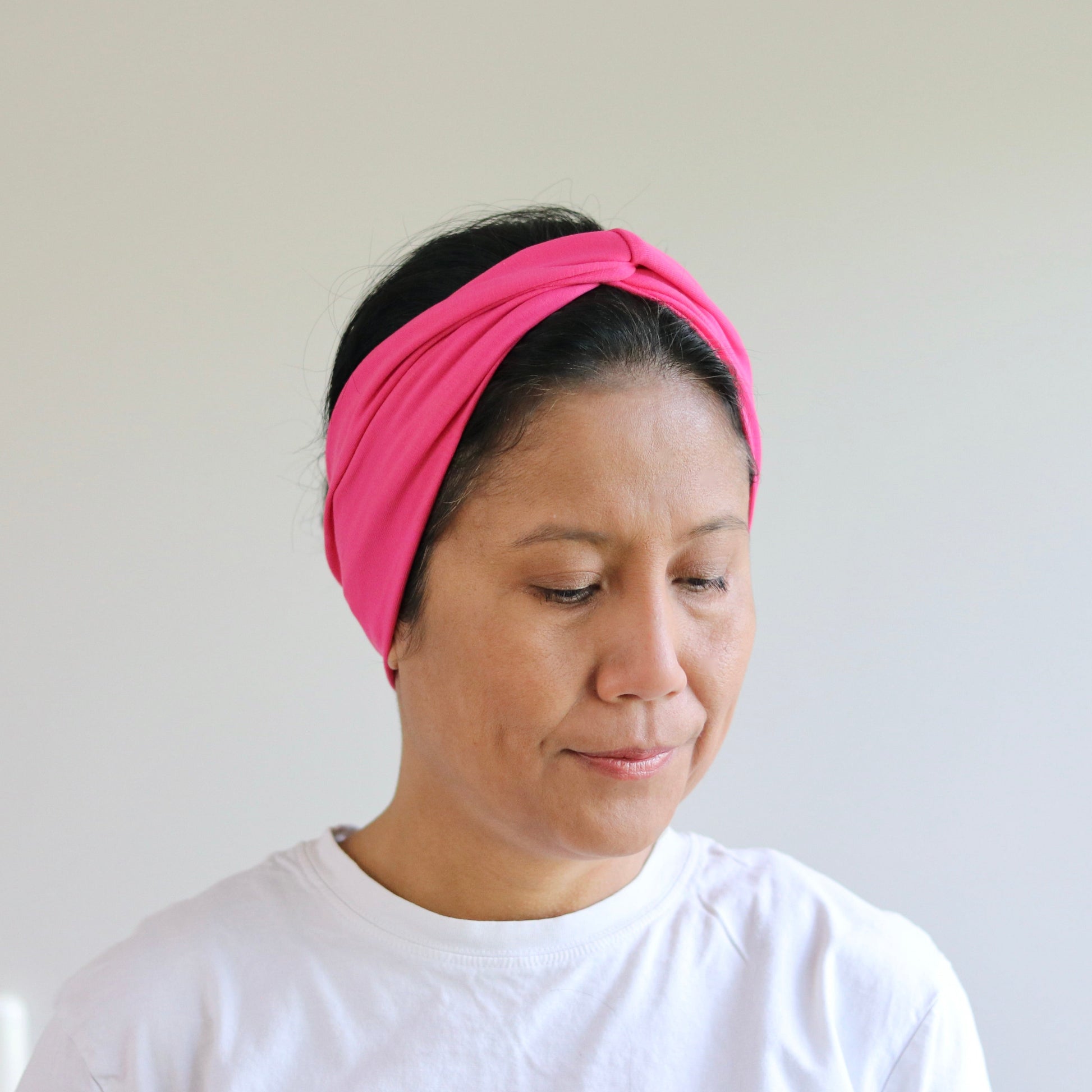 Woman wearing a pink headband against a plain background