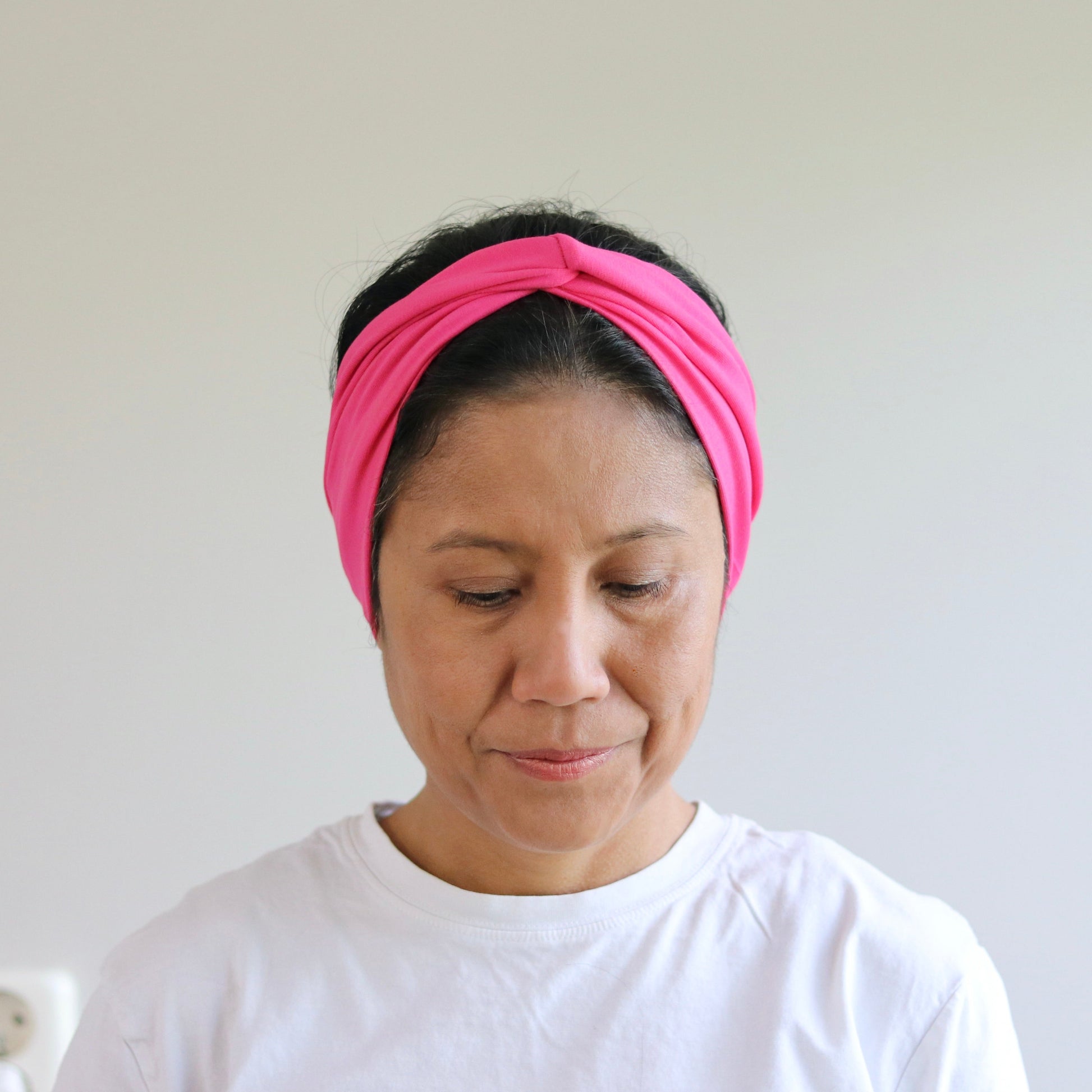 Woman wearing a pink headband against a plain background