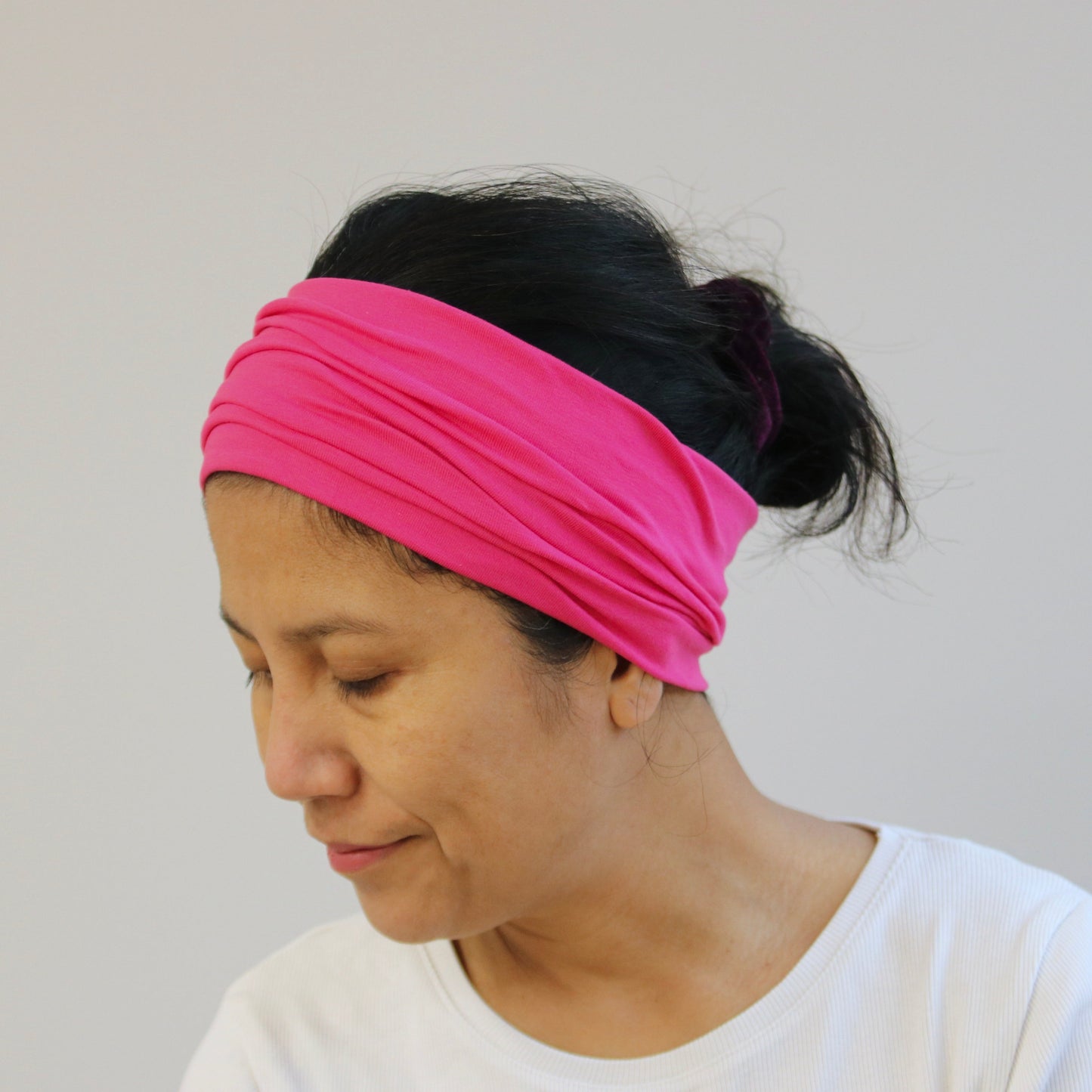 Woman wearing a pink headband against a plain background