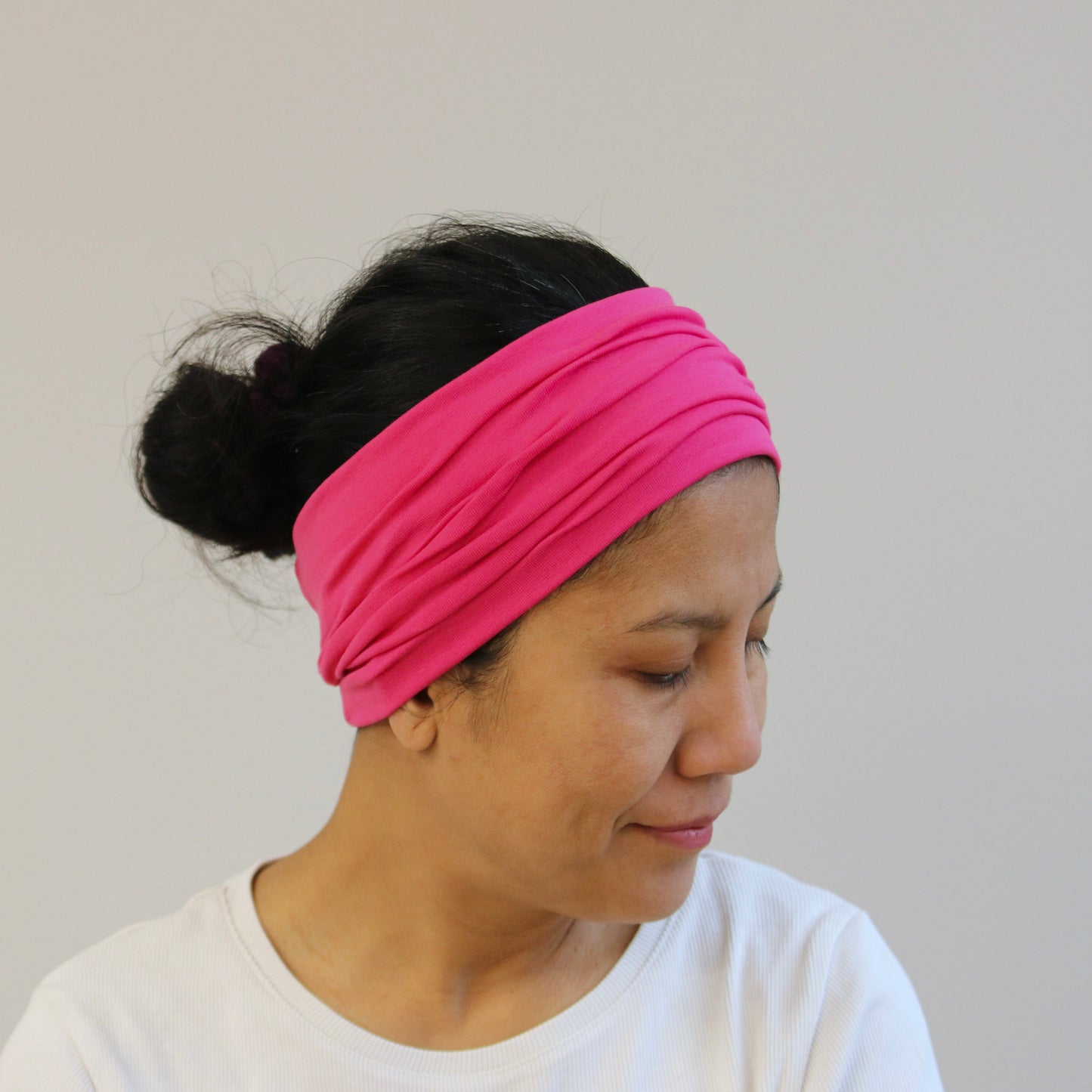 Person wearing a pink headband against a plain background