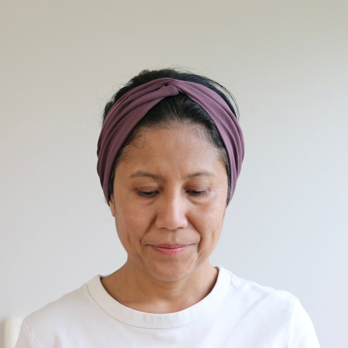 Woman wearing a purple headband against a plain background