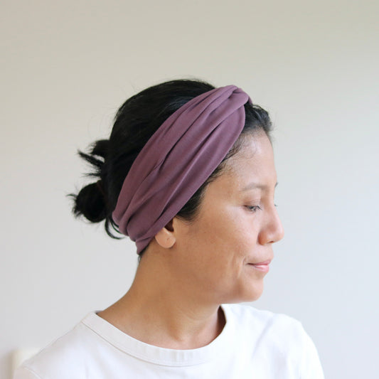 Woman wearing a purple headband against a plain background