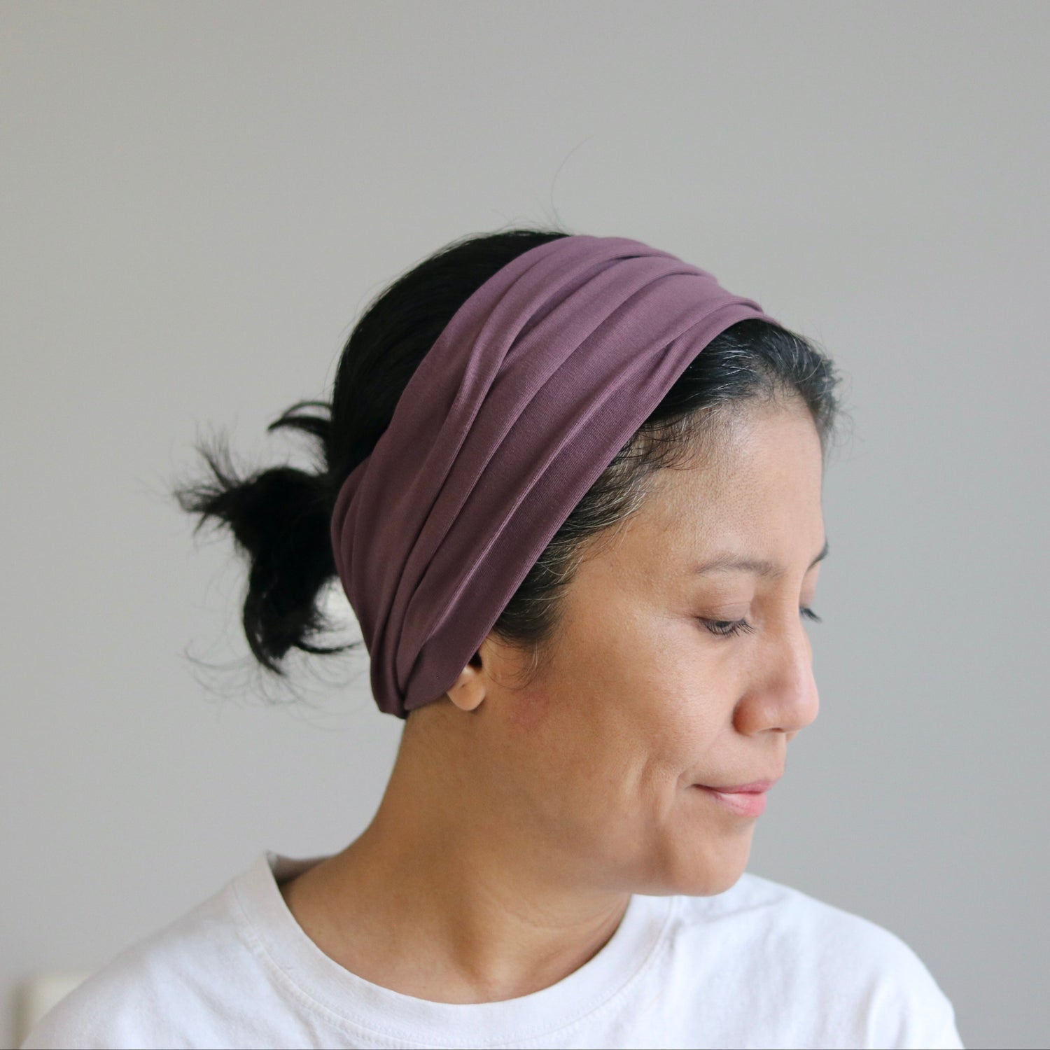 Woman wearing a purple headband against a plain background