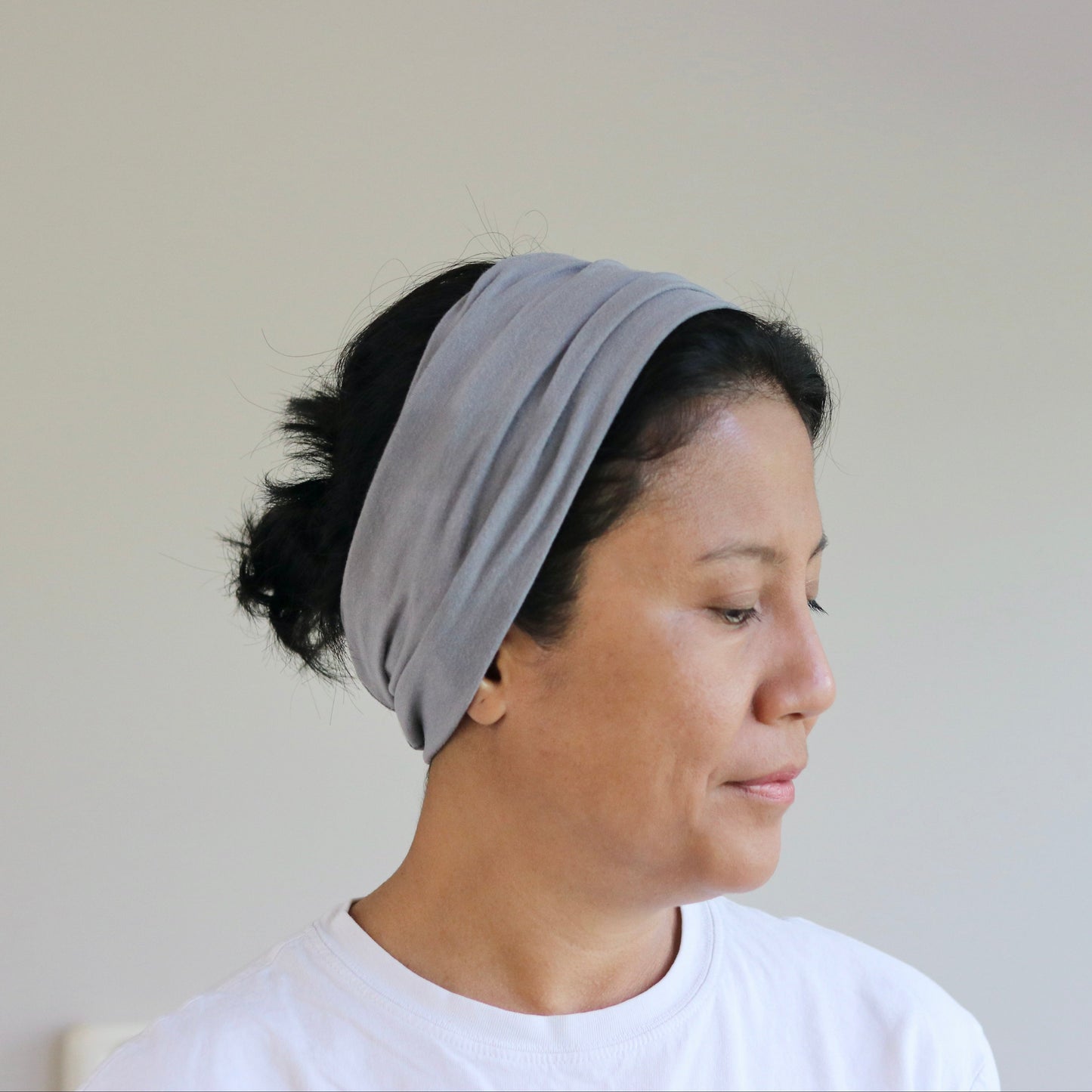 Woman wearing a gray headband against a plain background