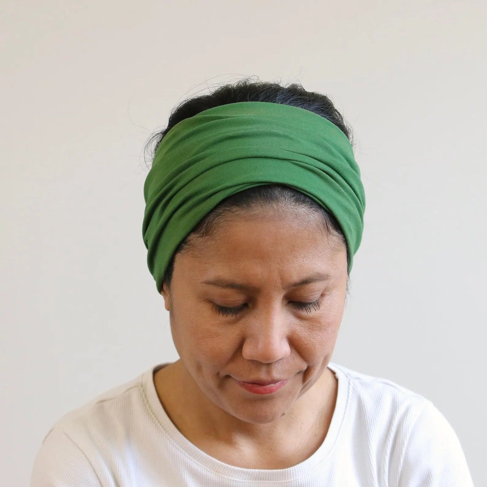 Woman wearing a green headband against a plain background