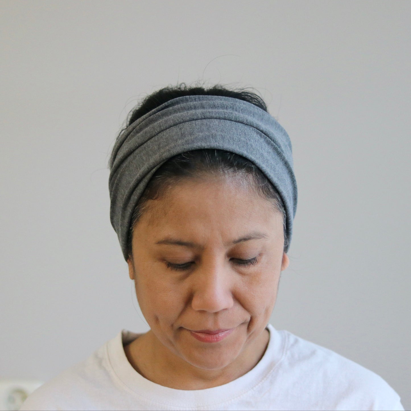 Woman wearing a gray headband against a plain background