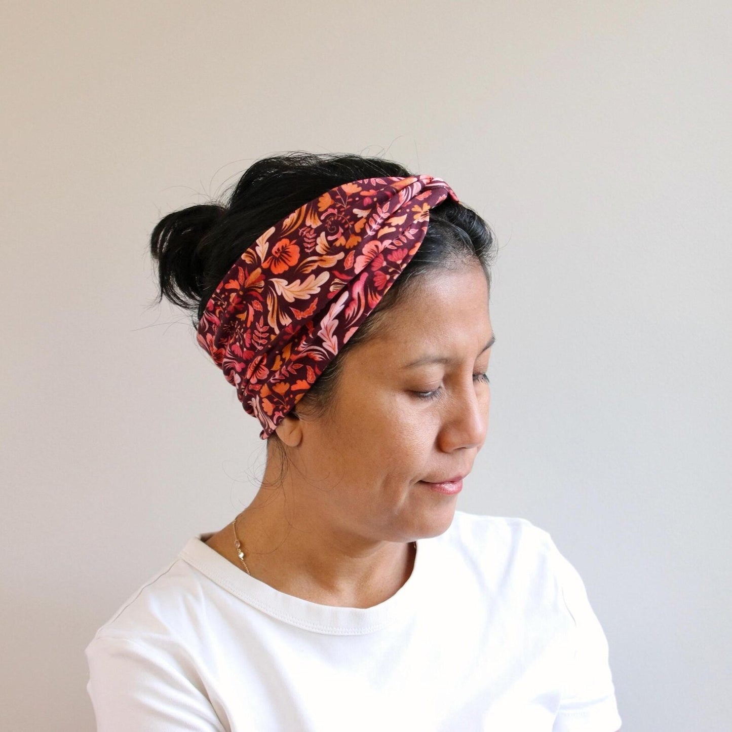 Woman wearing a red floral headband against a plain background