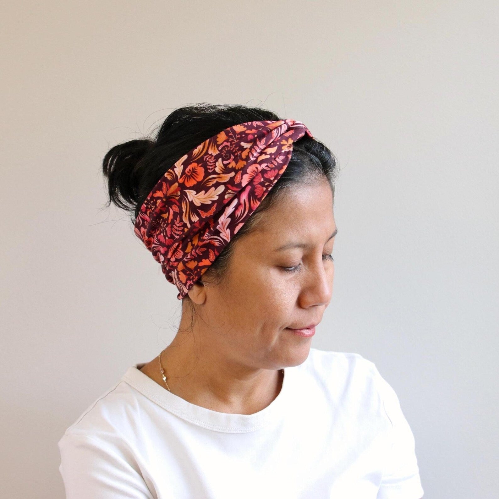 Woman wearing a red floral headband against a plain background