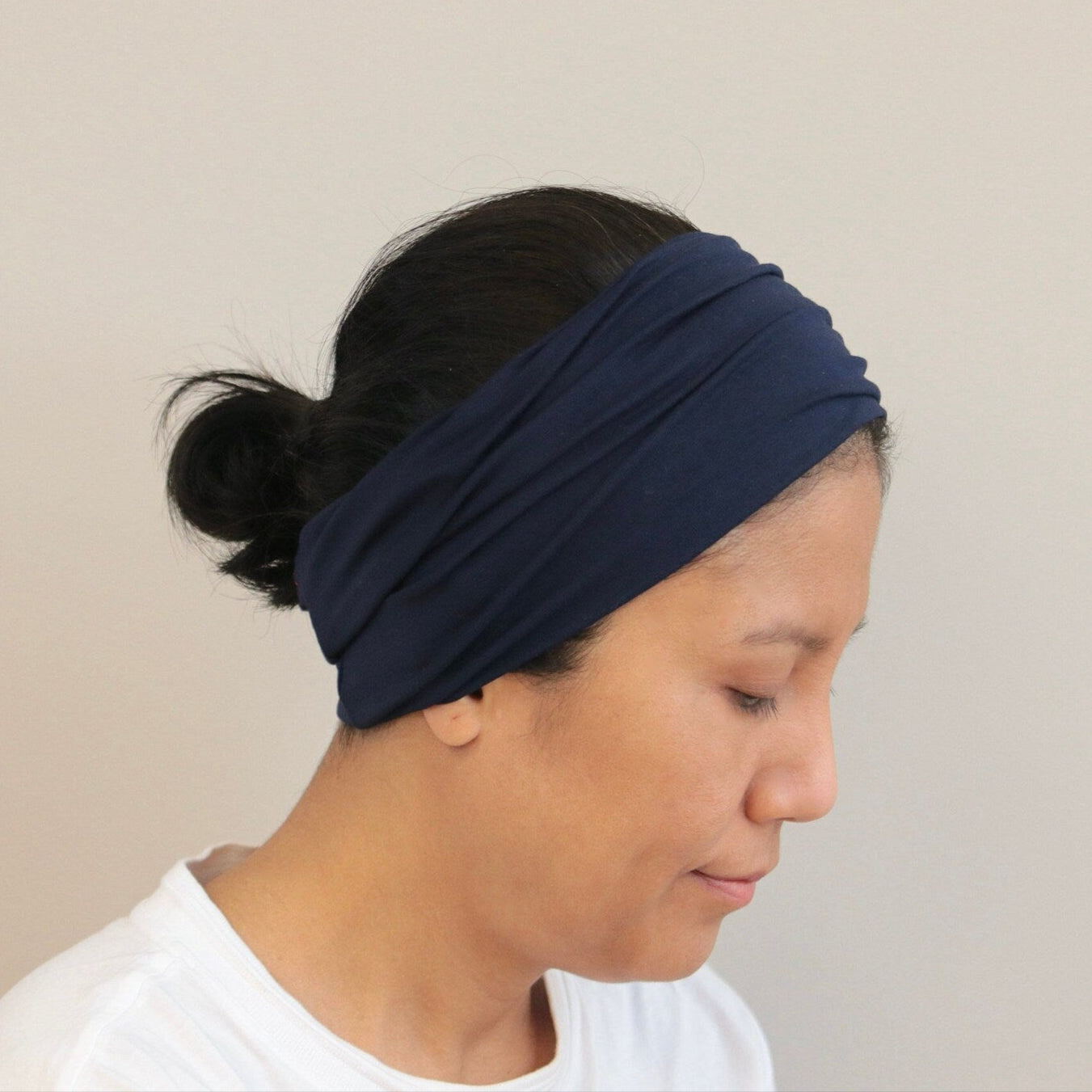 Person wearing a navy blue headband against a beige background