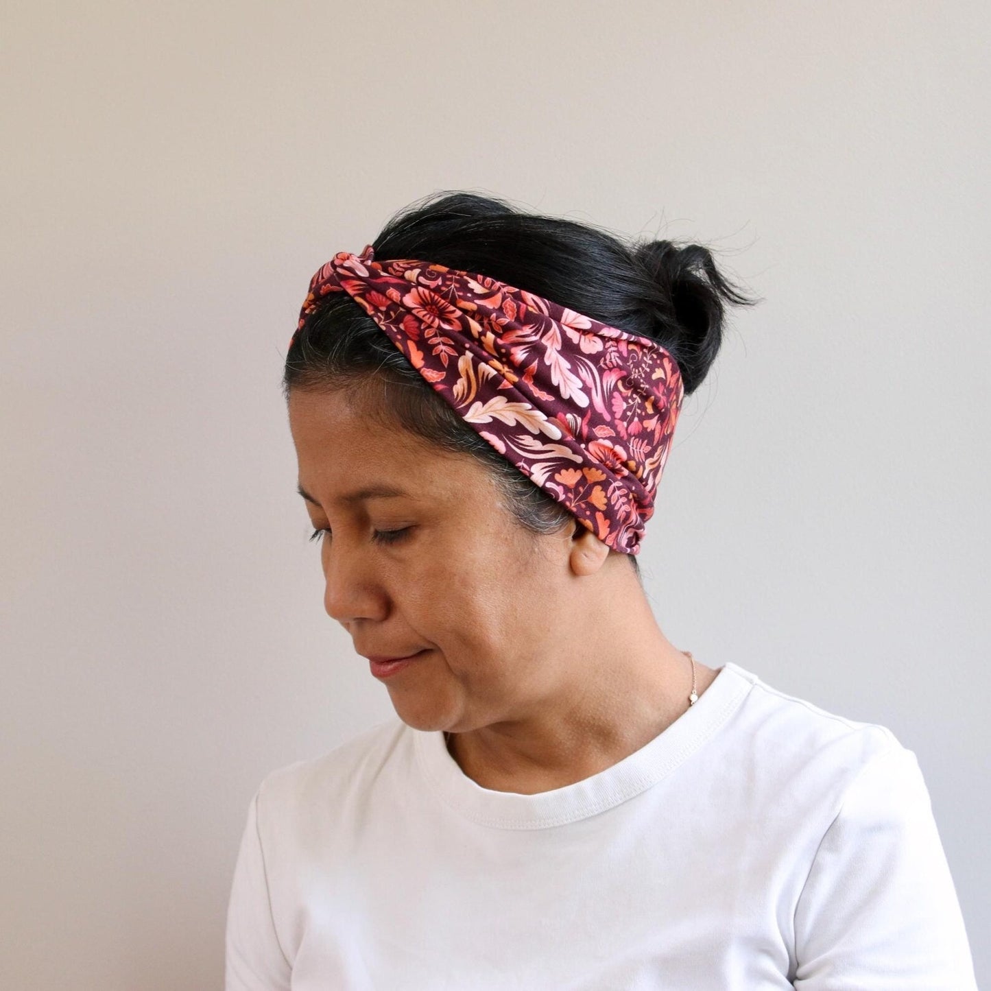 Person wearing a pink patterned headband against a plain background